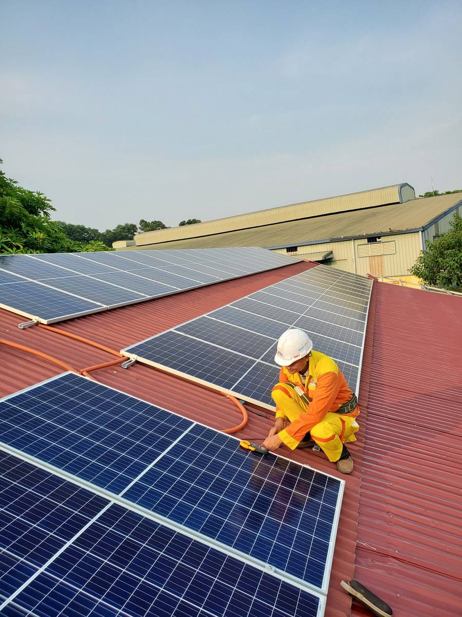 A SolarTNP technician inspecting a rooftop solar installation during a maintenance visit